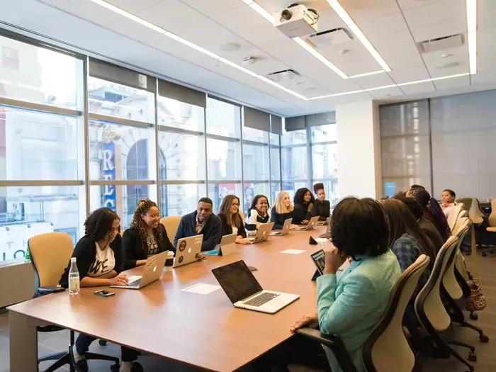 Group of professionals gathered around a large conference table using laptops and discussing ideas for Town Service Net